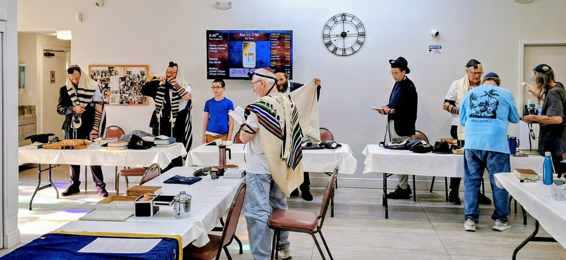 Weekday Shacharis minyan at Young Israel Chabad of Pembroke Pines with the DigitalShul zmanim display on the wall